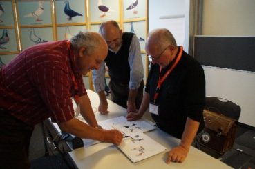 Heinrich Niederklopfer und Claude Schneider nutzten die Chance, um letzte Details an den Standardbildern der Schweizer Tauben mit dem Zeichner Jean-Louis Frindel abzusprechen. Foto: Bauer 